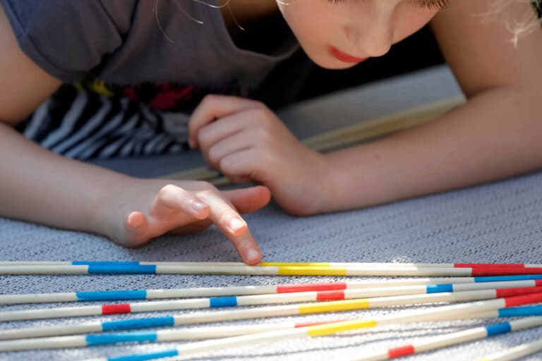 enfant concentré qui joue au jeu du mikado