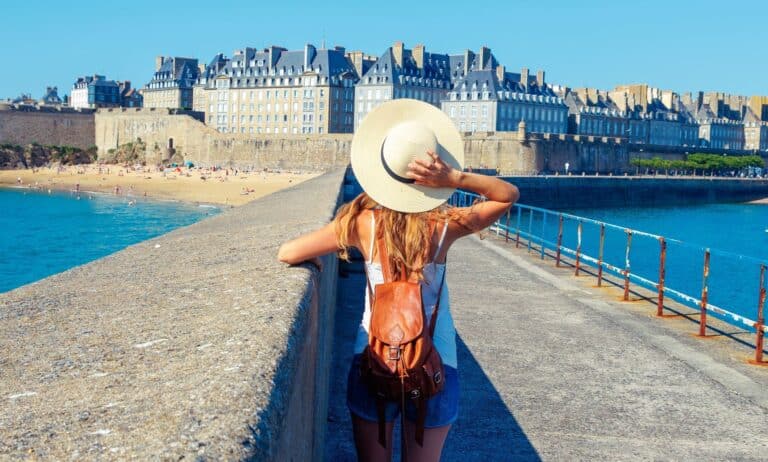 Votre programme de l'été à Saint-Malo ! 2 Jeune femme de dos caché sous son chapeau d'été qui admire intra-muros